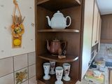 a corner shelf in the corner of a kitchen with cups and teapots on it