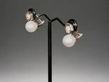a pair of silver and pearl earrings on a black stand