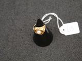 a gold ring with a pearl in it on a black surface
