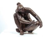 a bronze statue of a man sitting on a white surface