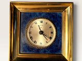 a gold clock with roman numerals in a gold frame