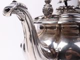 a silver tea pot with a bird on top of it