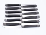six knives with black handles are on a white surface