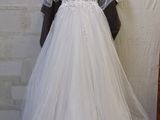 wedding dress hanging on a hanger in front of a brick wall