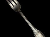 a silver fork with a silver handle on a black background