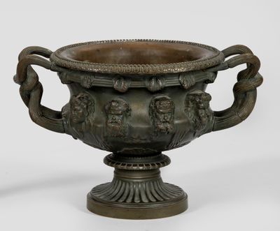 a bronze vase with two handles on a pedestal