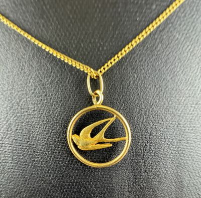 a gold necklace with a bird on it