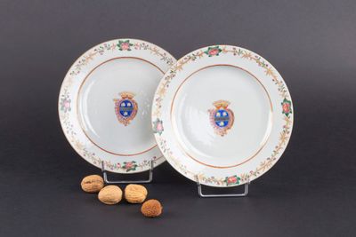 deux assiettes ornées d'un blason, à côté de noix