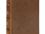 un vieux livre à la couverture brune posé sur une surface blanche