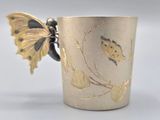 a silver cup with a gold butterfly on it