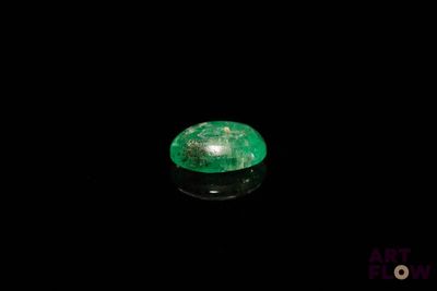 a close up of a green emerald on a black surface