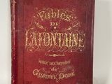an old red book with gold writing on it sitting on a white surface