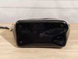 the small black purse is sitting on a wooden table