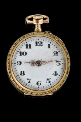 gros plan d'une montre de poche en or sur fond noir