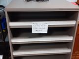 a gray bookcase with a sign on top of it