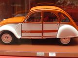 une voiture orange et blanche exposée dans une vitrine