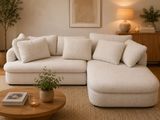 a white couch with pillows and a table with a potted plant on it
