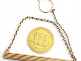 une pièce d'or suspendue à une chaîne en or, avec une paire de ciseaux