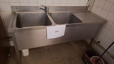 two sinks in a public restroom with a sign on the wall