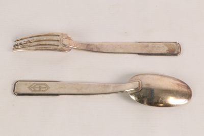 two silver spoons and a fork on a table