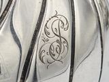 a close up of a silver vase with a monogram on it