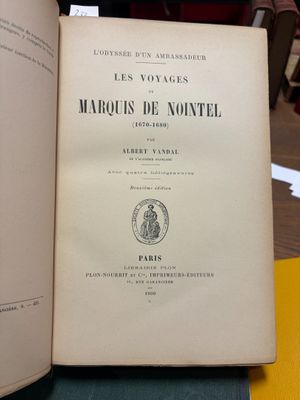 un livre ouvert posé sur une table, elle-même posée sur une autre table