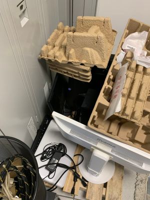 un écran d'ordinateur posé sur un bureau, à côté d'une pile de cartons