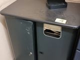 une poubelle noire posée à côté d'une poubelle en métal