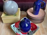 un vase bleu posé sur une assiette, à côté d'un autre vase bleu, sur un plancher en bois