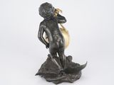 bronze figurine of a boy on a rock with a gold bell