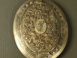 a silver pocket watch on a table with a clock on it
