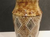 a brown and white vase sitting on a white table