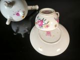 a tea pot and saucer sitting on a table