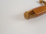 a small wooden object with a brass handle on a white surface
