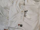 three pairs of white t - shirts sitting on top of a white table