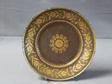 a brown and gold plate with a flower design on it
