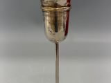 a silver cup with a red handle on a stand