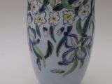 un vase blanc orné de fleurs bleues et jaunes