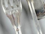 a lot of silver spoons and forks sitting on a table
