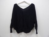 a black sweater hanging on a hanger against a white wall