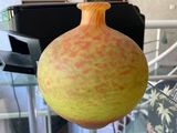 un vase jaune posé sur une table en verre dans un salon