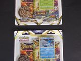 deux paquets de cartes à collectionner Pokémon posés sur une surface noire