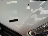 the front end of a white car with a sticker on it ' s hood