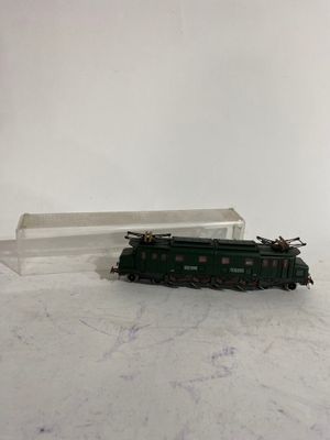 un petit train posé sur une surface blanche, avec une boîte en arrière-plan