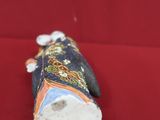 a small figurine of a woman sitting on a red surface