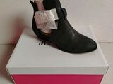 black leather ankle boots with a bow on top of a white box