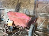 a red wheelbarrow in a barn that is being used as a wheelbarrow