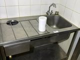 a sink and a trash can in a public restroom