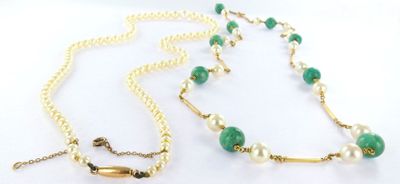 a close up of a necklace with pearls and a green bead