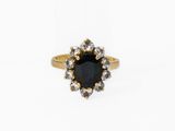 une bague en or sertie d'une pierre noire entourée de diamants blancs
